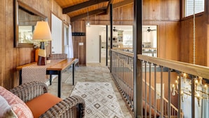 Un interior de madera con una escalera, un comedor y una cocina visible a través de una puerta abierta.