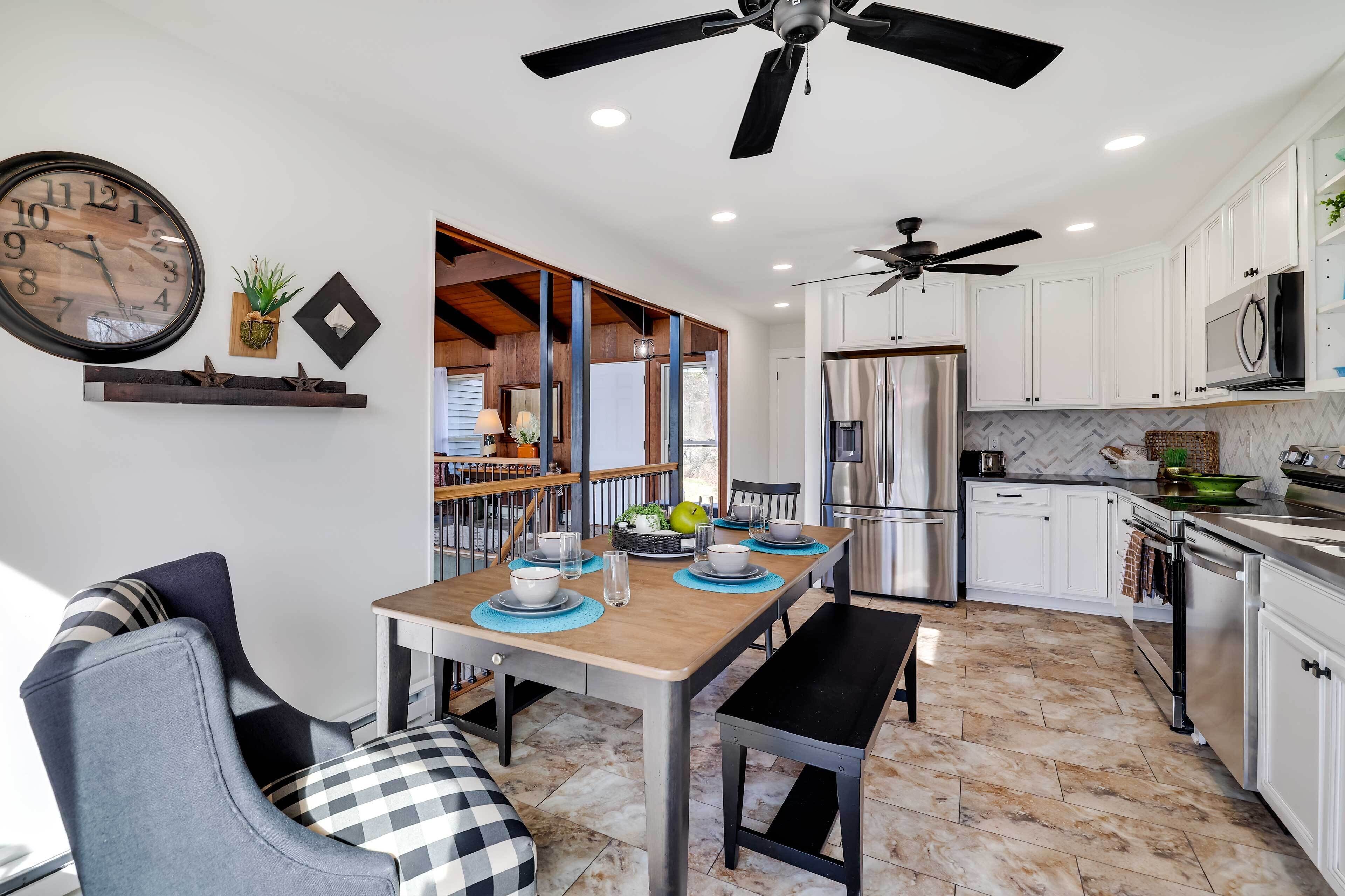 A modern kitchen with white cabinets, stainless steel appliances, and a dining area with a wooden table and chairs.