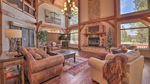 A spacious living room with a fireplace, wooden beams, and large windows. - Grand Angel Fire Retreat w/ Hot Tub & Fire Pit! (Angel Fire)