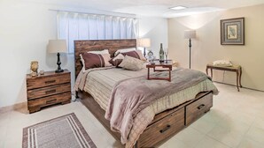 A bedroom with a wooden bed, bedside tables, a nightstand, a lamp, a framed picture on the wall, and a window with curtains. - Contemporary Cincinnati Apt w/ Wifi, Near Kenwood! (Cincinnati)