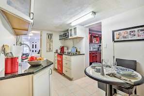 Uma cozinha compacta com micro-ondas, pia e área de refeições com mesa posta para dois.