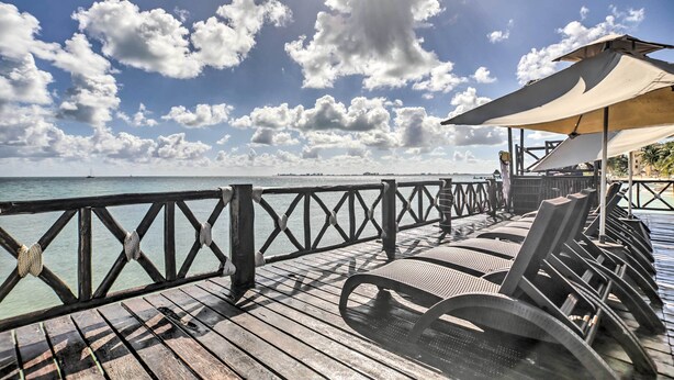 A wooden deck with lounge chairs and umbrellas overlooking a body of water. - Private Balcony w/ Views: Oceanfront Cancun Condo! (Cancun)
