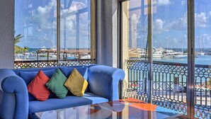 A balcony with a blue sofa, a glass table, and a view of a marina with boats. - Private Balcony w/ Views: Oceanfront Cancun Condo! (Cancun)