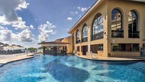 A pool area with clear blue water, a bar, and a building with arched windows and balconies. - Private Balcony w/ Views: Oceanfront Cancun Condo! (Cancun)