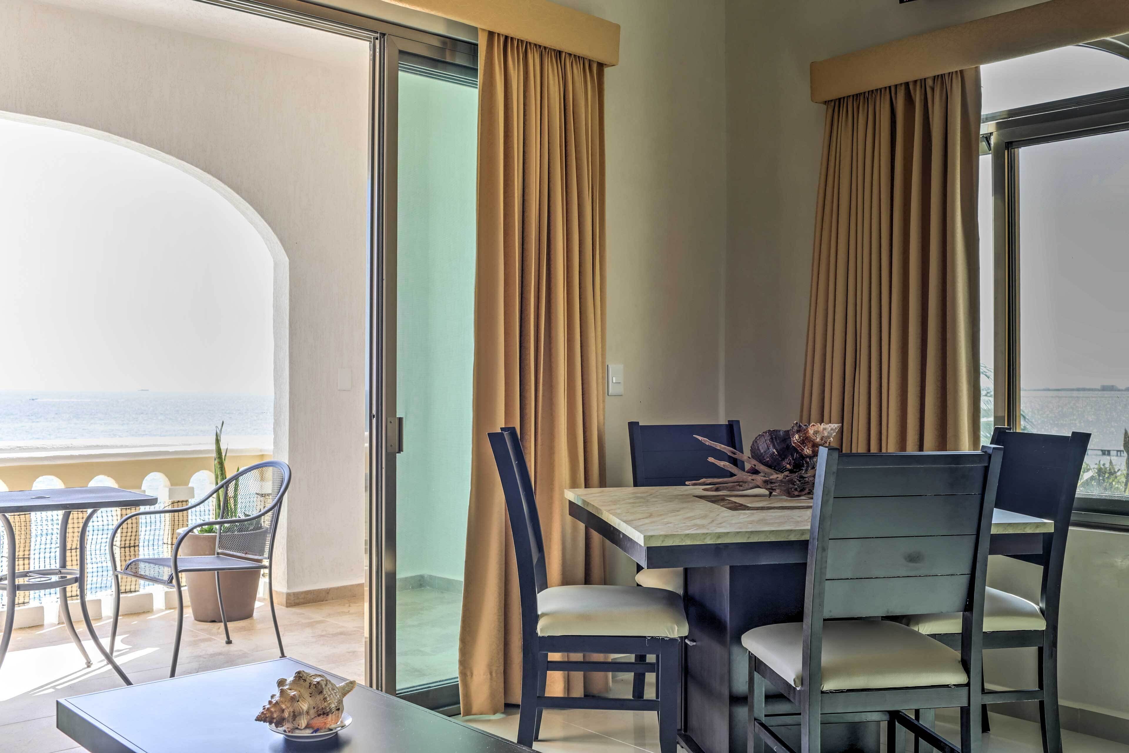A dining area with a table, chairs, and a view of the sea.