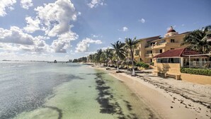 A beachfront hotel with clear turquoise water, palm trees, and a red-roofed building. - Private Balcony w/ Views: Oceanfront Cancun Condo! (Cancun)