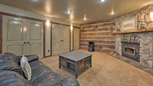 Una sala de estar acogedora con chimenea de piedra, un sofá grande y una mesa de centro.
