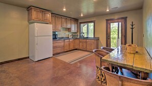 Una cocina con armarios de madera, un refrigerador, un microondas y una mesa de comedor con sillas.