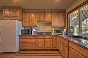 Una cocina con gabinetes de madera, un refrigerador, un microondas y una cafetera.