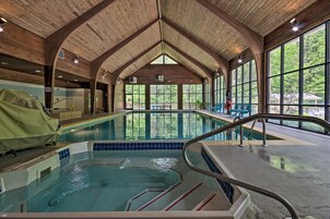 Una piscina interior con vigas de madera y grandes ventanales.