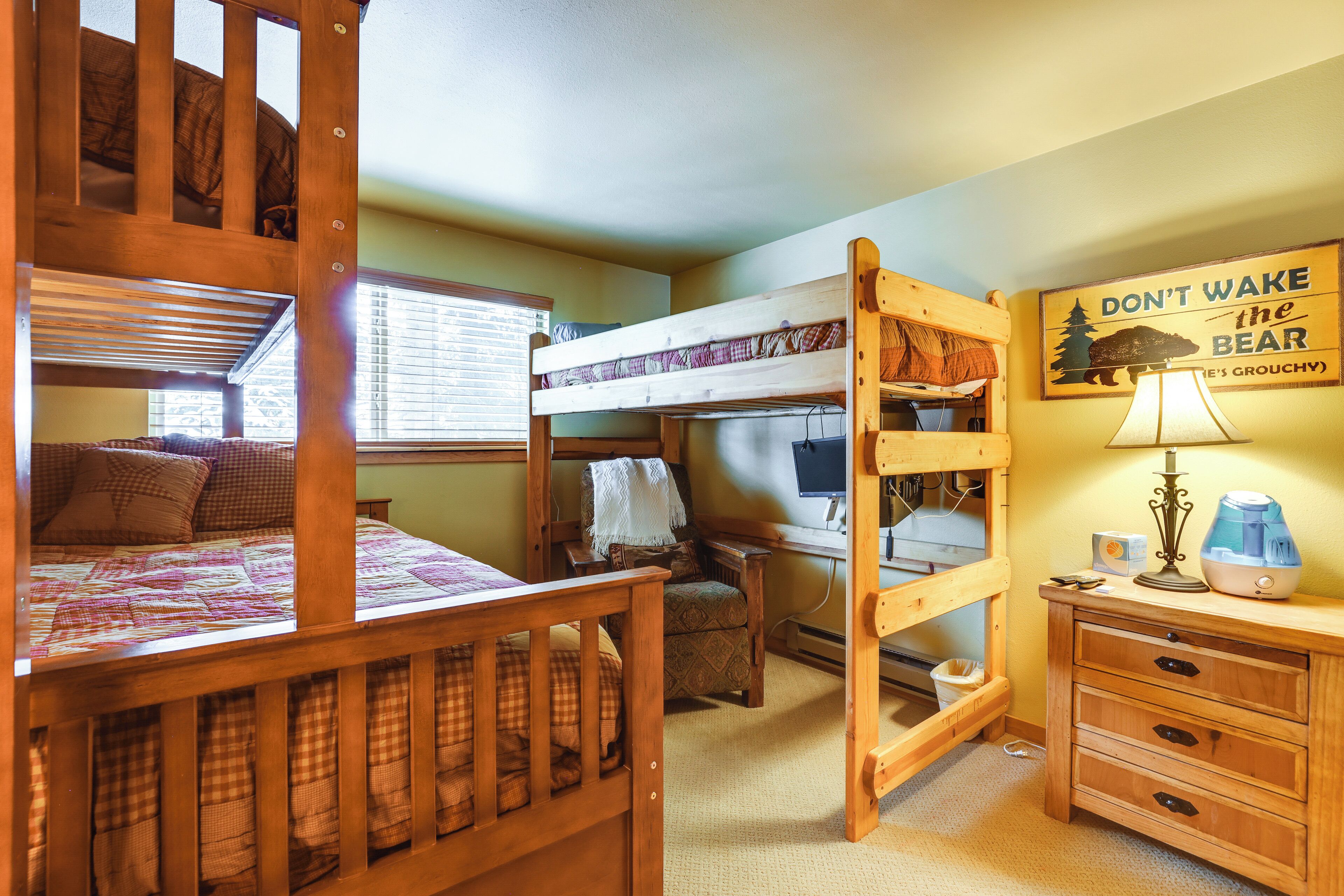A bunk bed room with a desk, chair, and a sign on the wall.