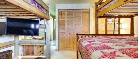 A bunk bed room with a television, wooden furniture, and a closet.