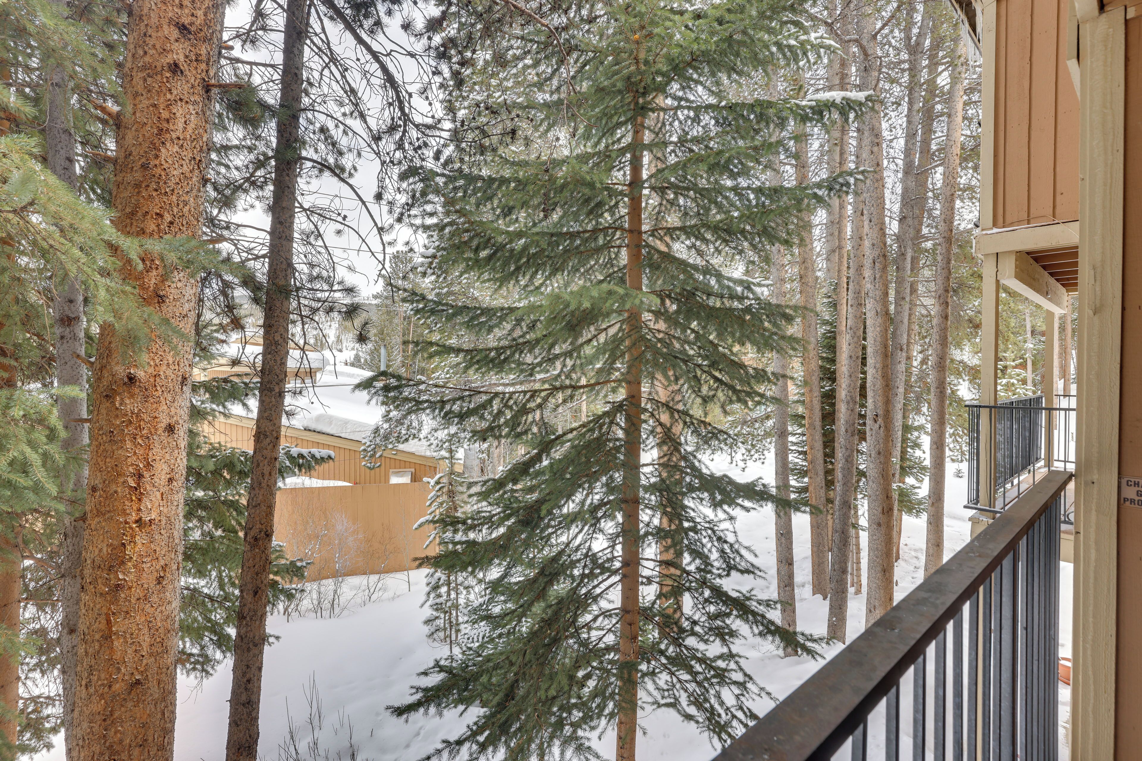 A wooden cabin with a balcony overlooking a snowy forest.