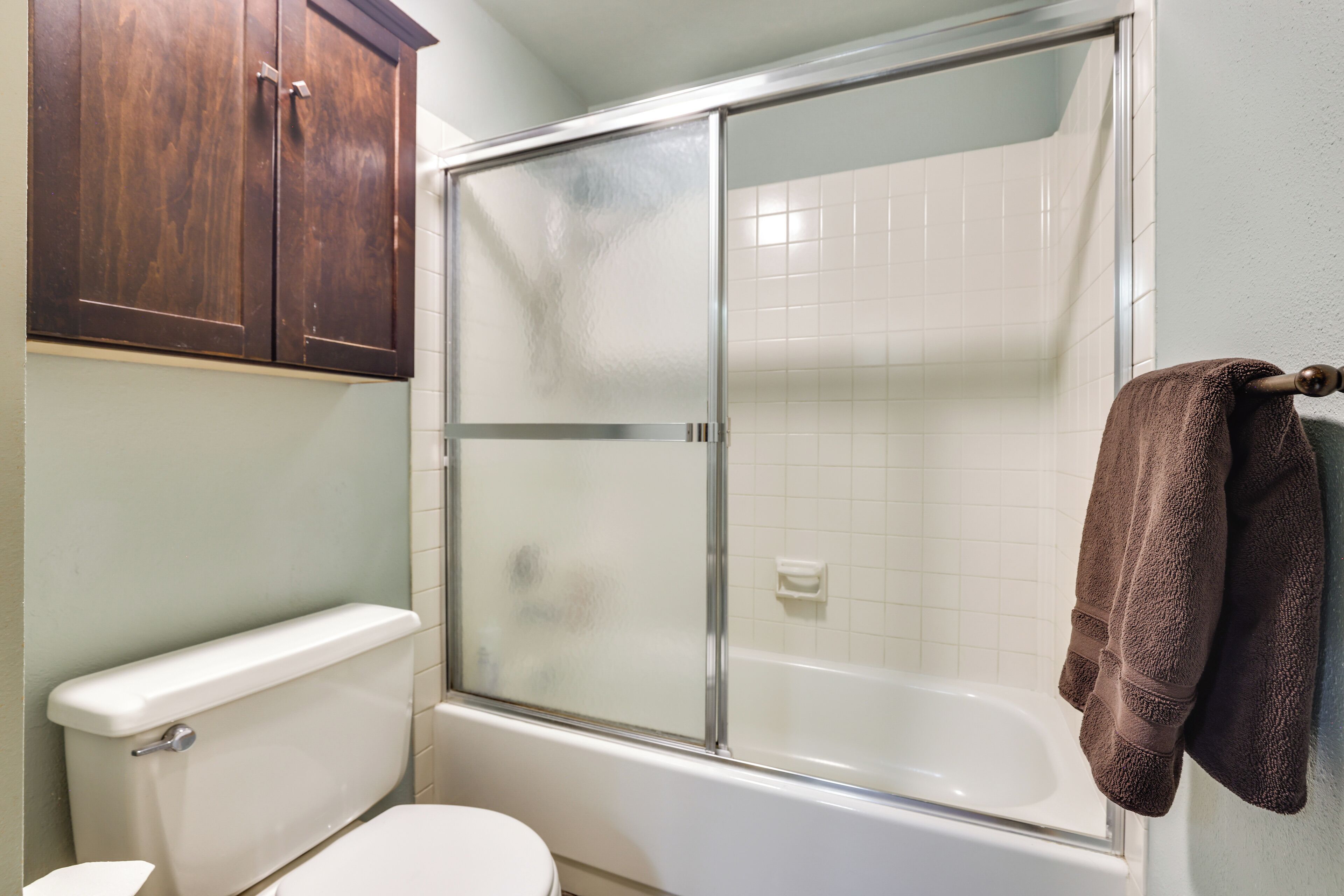 Une salle de bain équipée de toilettes, d’une douche et d’un porte-serviettes mural.