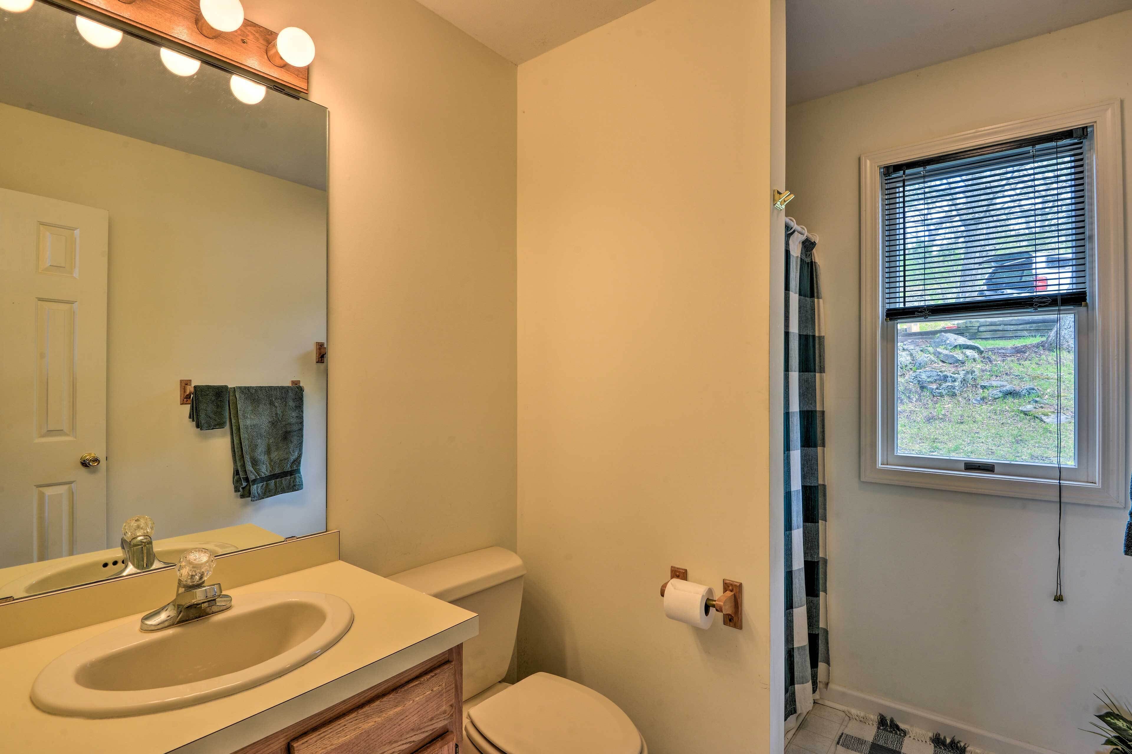 Un baño con lavabo, espejo, inodoro y ventana.
