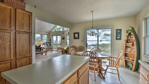 A spacious kitchen with wooden cabinets, a large island, and a dining area with chairs and a table.