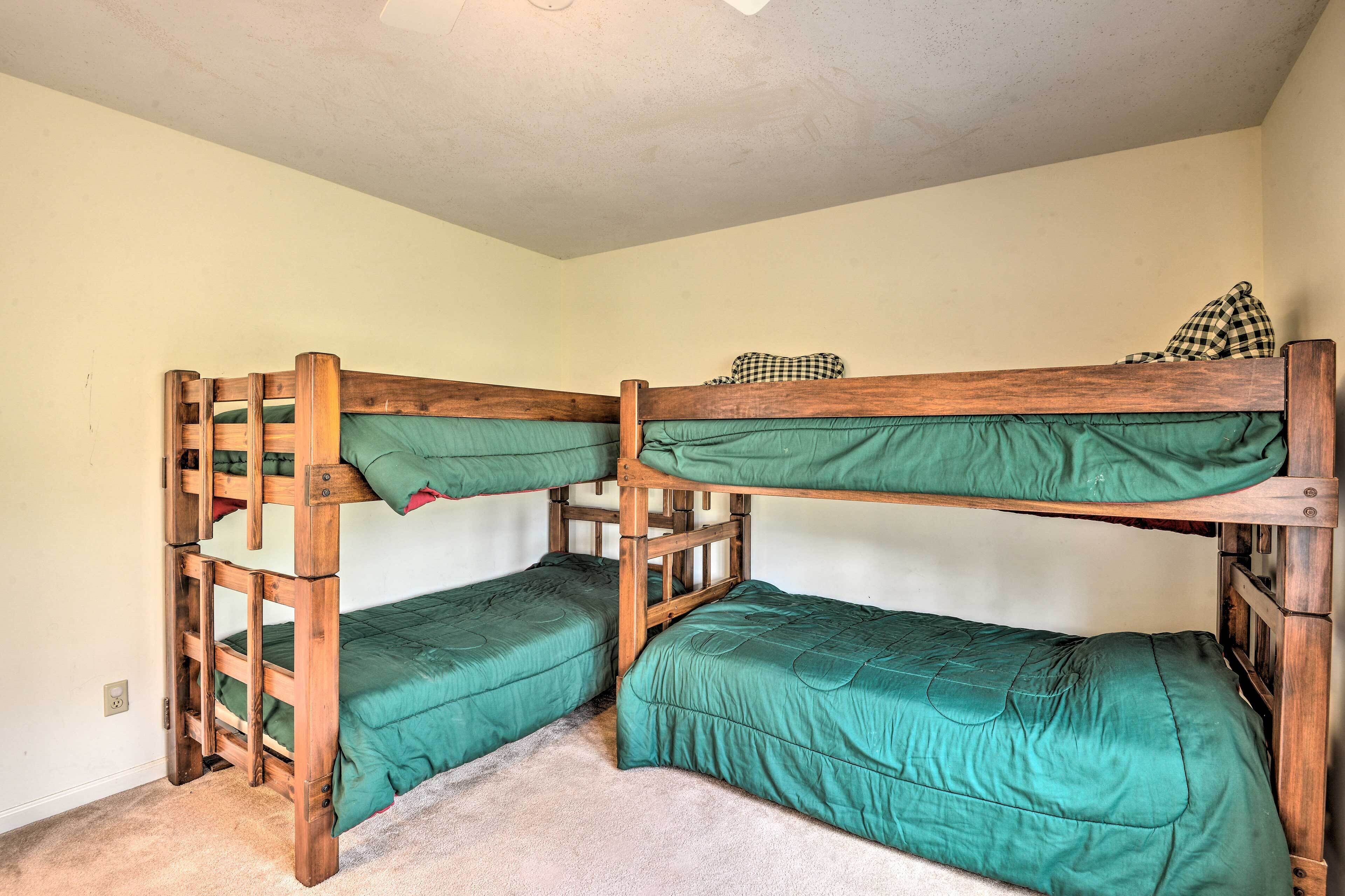 A bunk bed room with two wooden bunk beds, each with green bedding.