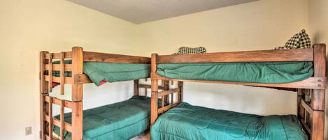 A bunk bed room with two wooden bunk beds, each with green bedding.