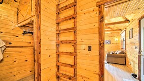 Un interior de madera con una escalera, un sofá y una puerta que da a otra habitación.