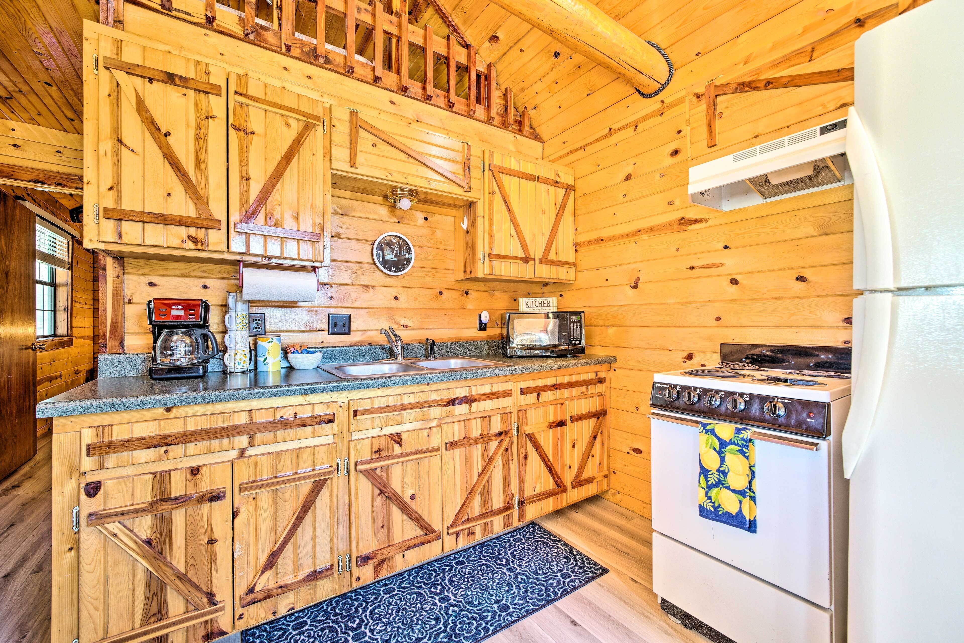 A wooden cabin kitchen with a stove, microwave, and coffee maker.