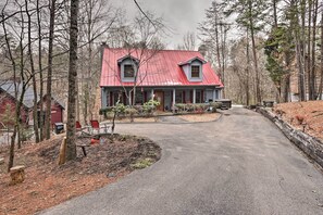 A two-story house with a red roof, surrounded by trees and a paved driveway. - Pigeon Forge Cabin w/ Hot Tub, 12 Mi to Dollywood! (Sevierville)
