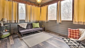 Ein gemütliches Zimmer mit einer Couch, einem Sessel, einer Lampe und einem Fenster mit Vorhängen.