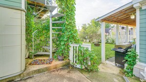 A covered patio area with a wooden deck, a white fence, and a green wall with climbing plants. - Epic Brunswick Apartment With Hot Tub! (Brunswick)