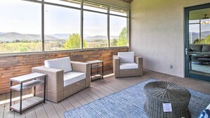Ein sonnendurchfluteter Raum mit Korbmöbeln und Blick auf die Landschaft, mit einem großen Fenster.