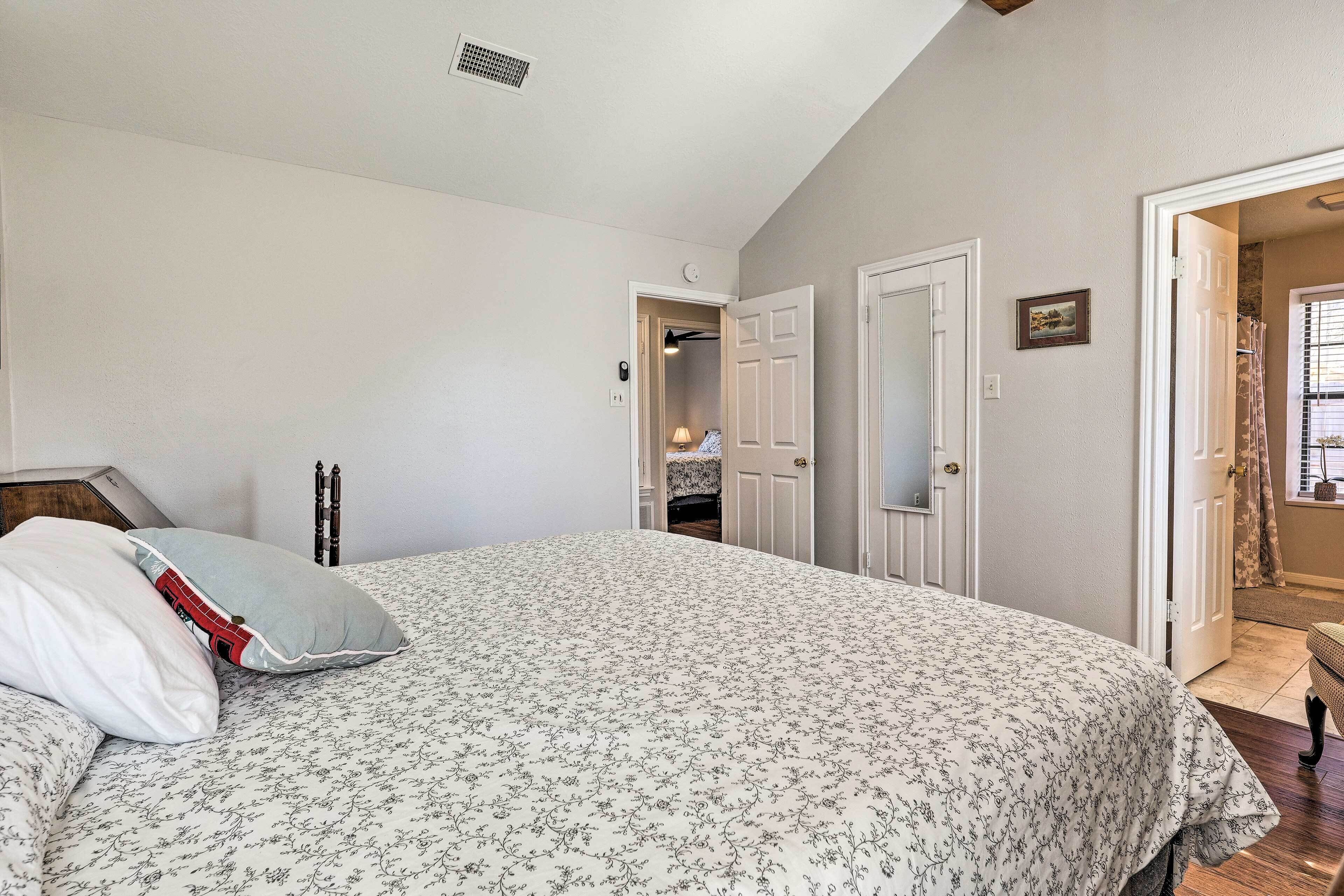 Une chambre à coucher avec un grand lit, un placard et une salle de bain visible à travers une porte ouverte.