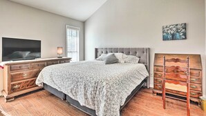 Ein Schlafzimmer mit Bett, Kommode, Fernseher und Kunstwerken.