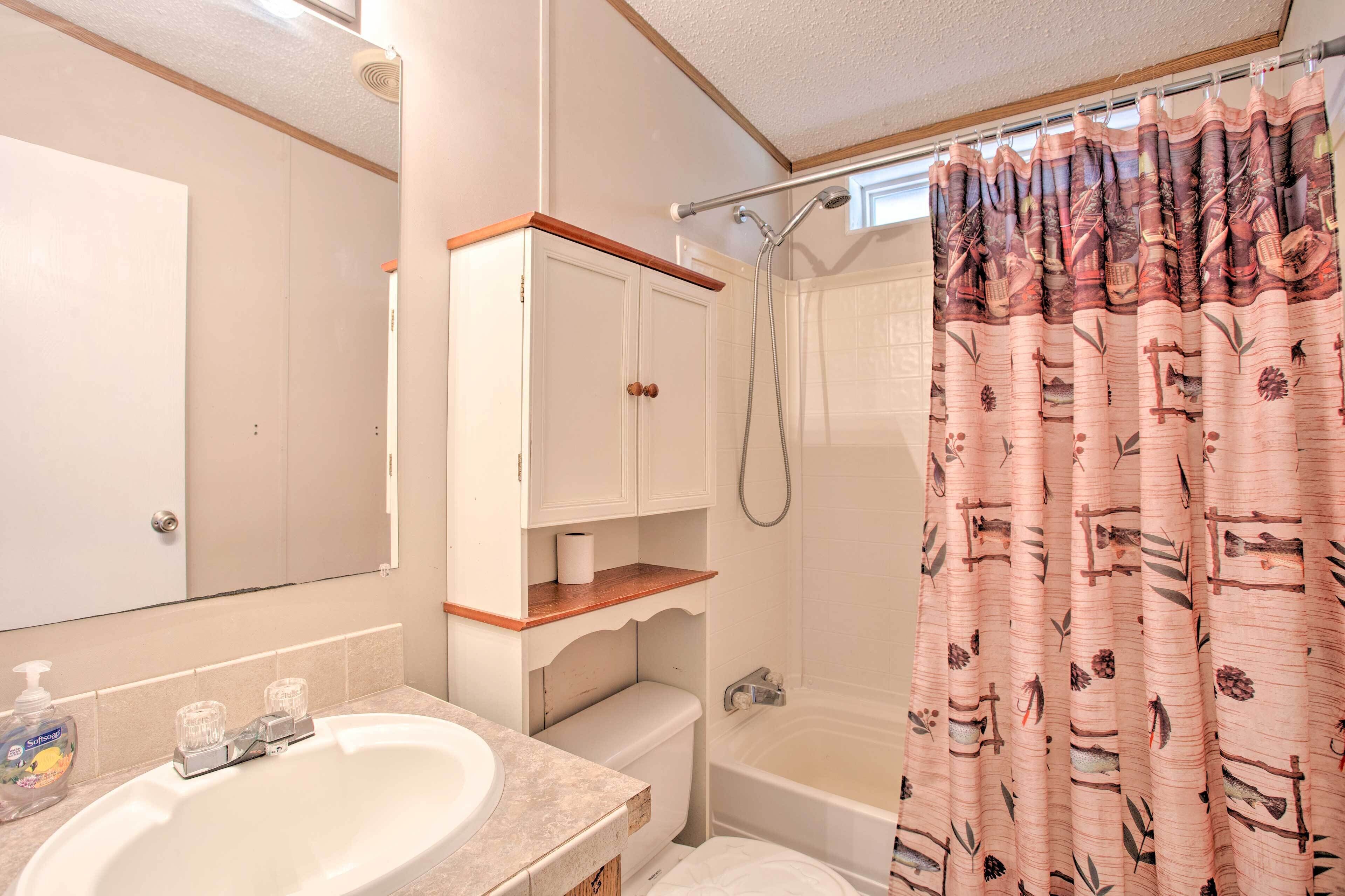 A bathroom with a sink, toilet, shower, and a mirror.