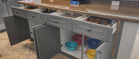 A kitchen with open drawers, a countertop, and a view of an outdoor area.