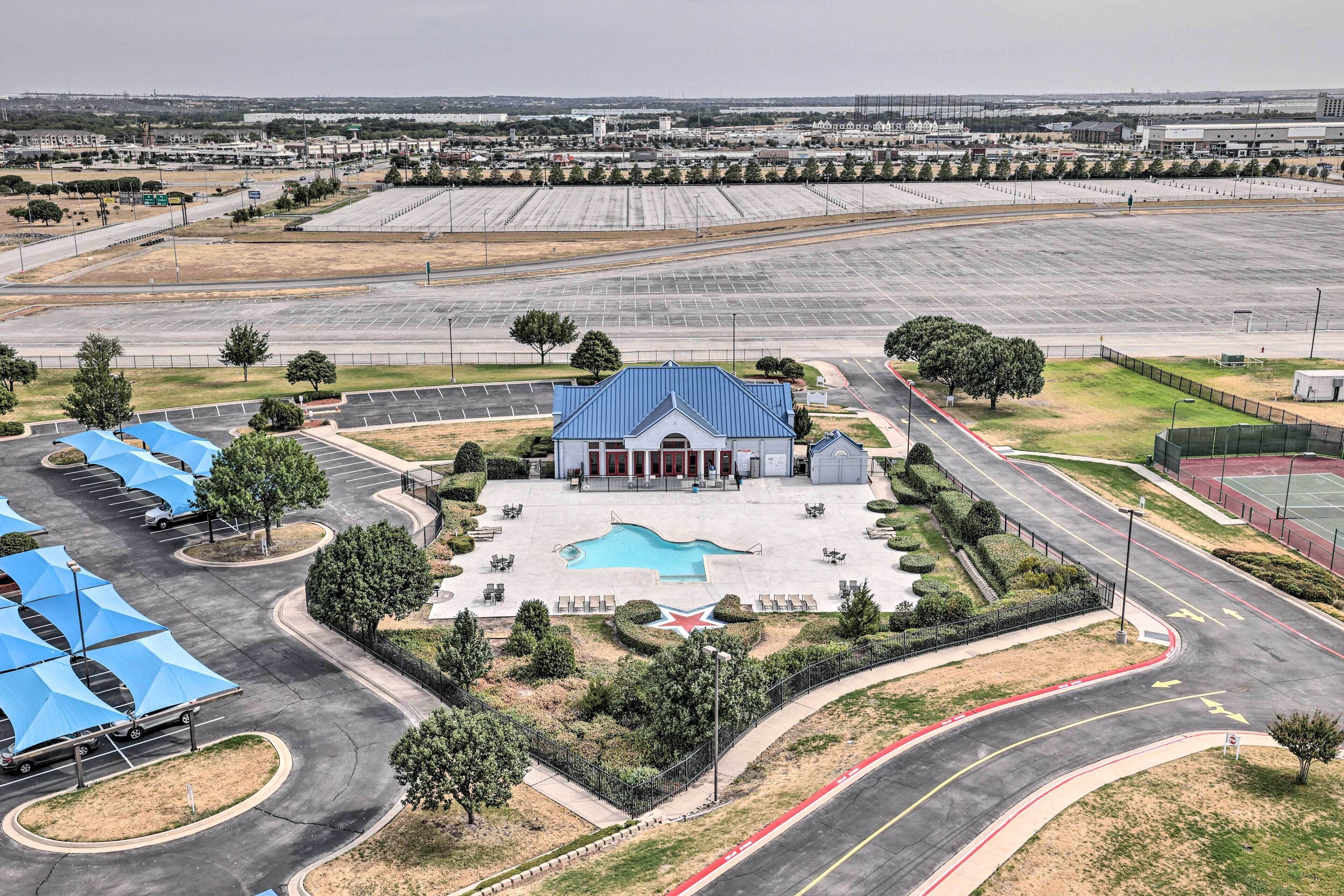 A large parking lot with a swimming pool, a building with a blue roof, and a star-shaped garden.