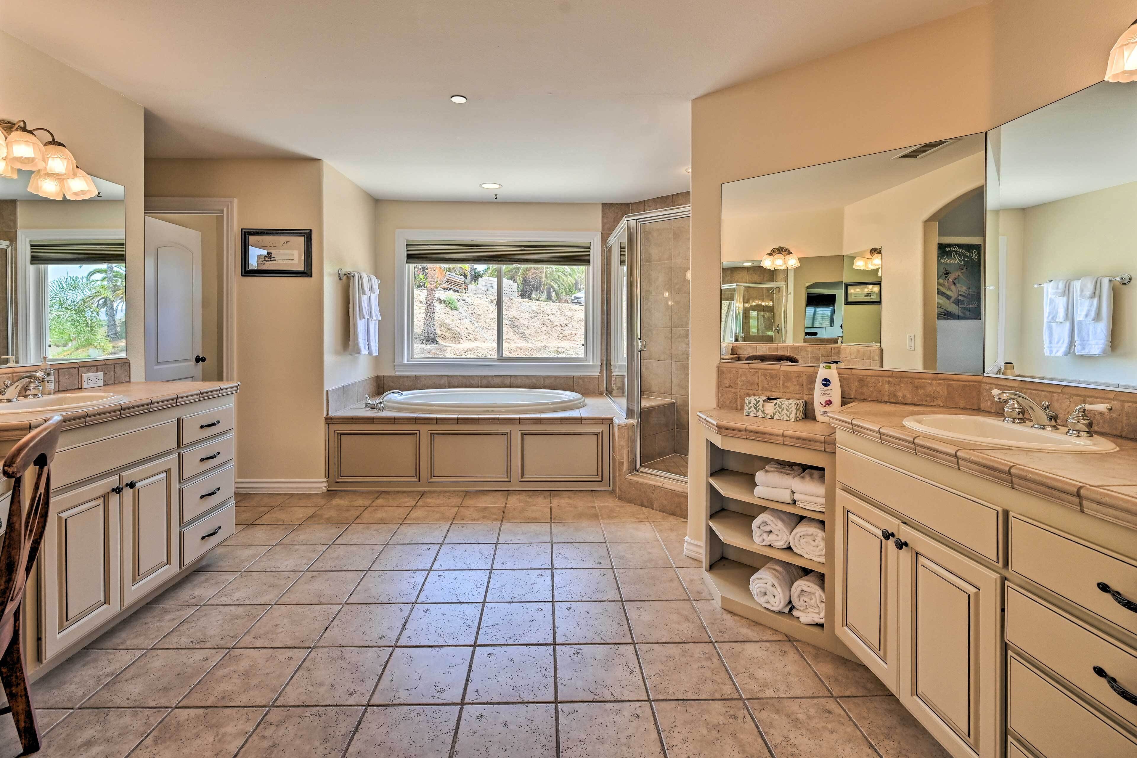 A spacious bathroom with a large bathtub, two sinks, and a walk-in shower.