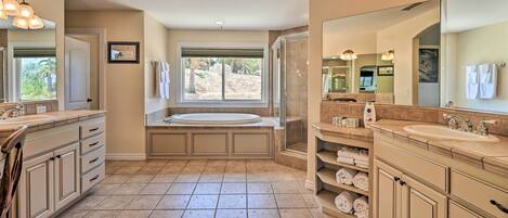A spacious bathroom with a large bathtub, two sinks, and a walk-in shower.