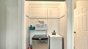A compact kitchenette with a microwave, a small sink, and a compact refrigerator.