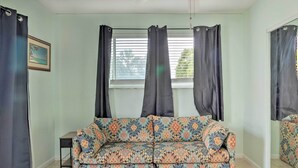 A room with a patterned sofa, a small table, and a window with curtains.