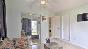 A living room with a sofa, a glass coffee table, and a ceiling fan.