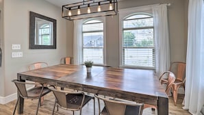 Une salle à manger avec une grande table en bois, des chaises en métal et un luminaire suspendu.