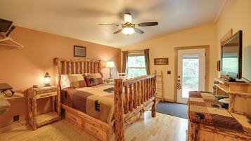 A bedroom with a wooden bed, a ceiling fan, a television, and a door with a window.