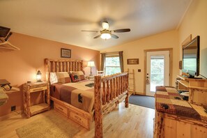 A bedroom with a wooden bed, a ceiling fan, a television, and a door with a window.
