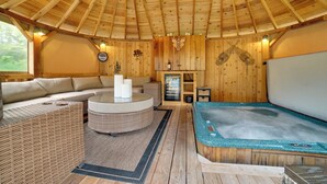 A wooden interior with a sofa, a round table, a hot tub, and a fireplace. - 'moose Lodge' Cabin w/ Entertainment Gazebo! (Baring)