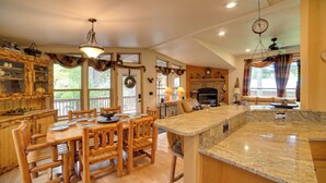 A spacious kitchen with wooden furniture, a granite countertop, and a fireplace. - 'moose Lodge' Cabin w/ Entertainment Gazebo! (Baring)
