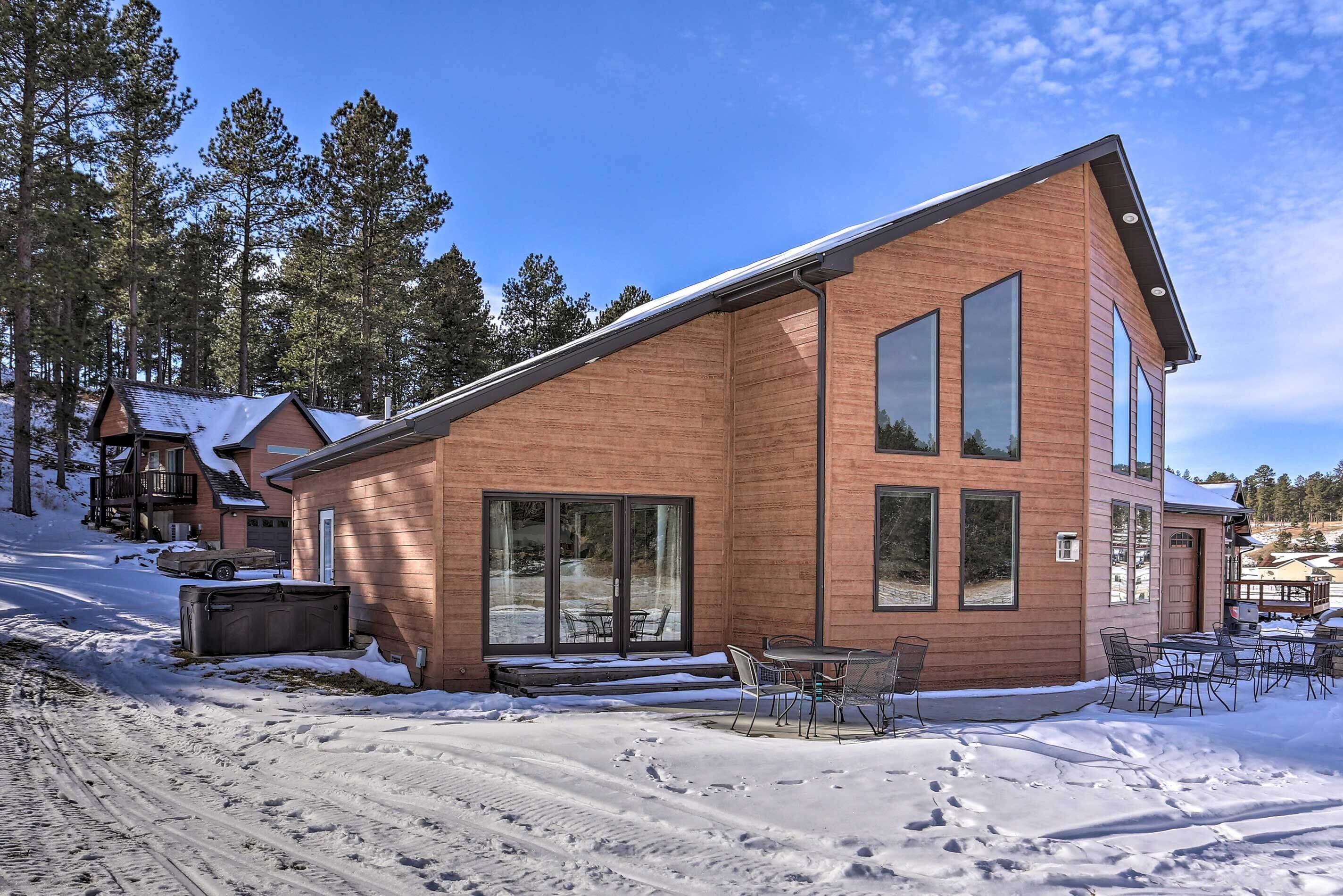 A modern wooden house with large windows and a patio area.