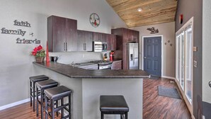 A modern kitchen with dark wood cabinets, a central island with stools, stainless steel appliances, and a ceiling with exposed beams. - 'hakuna Matata Cabin' - 11 Mi to Mt Rushmore! (Rapid City)