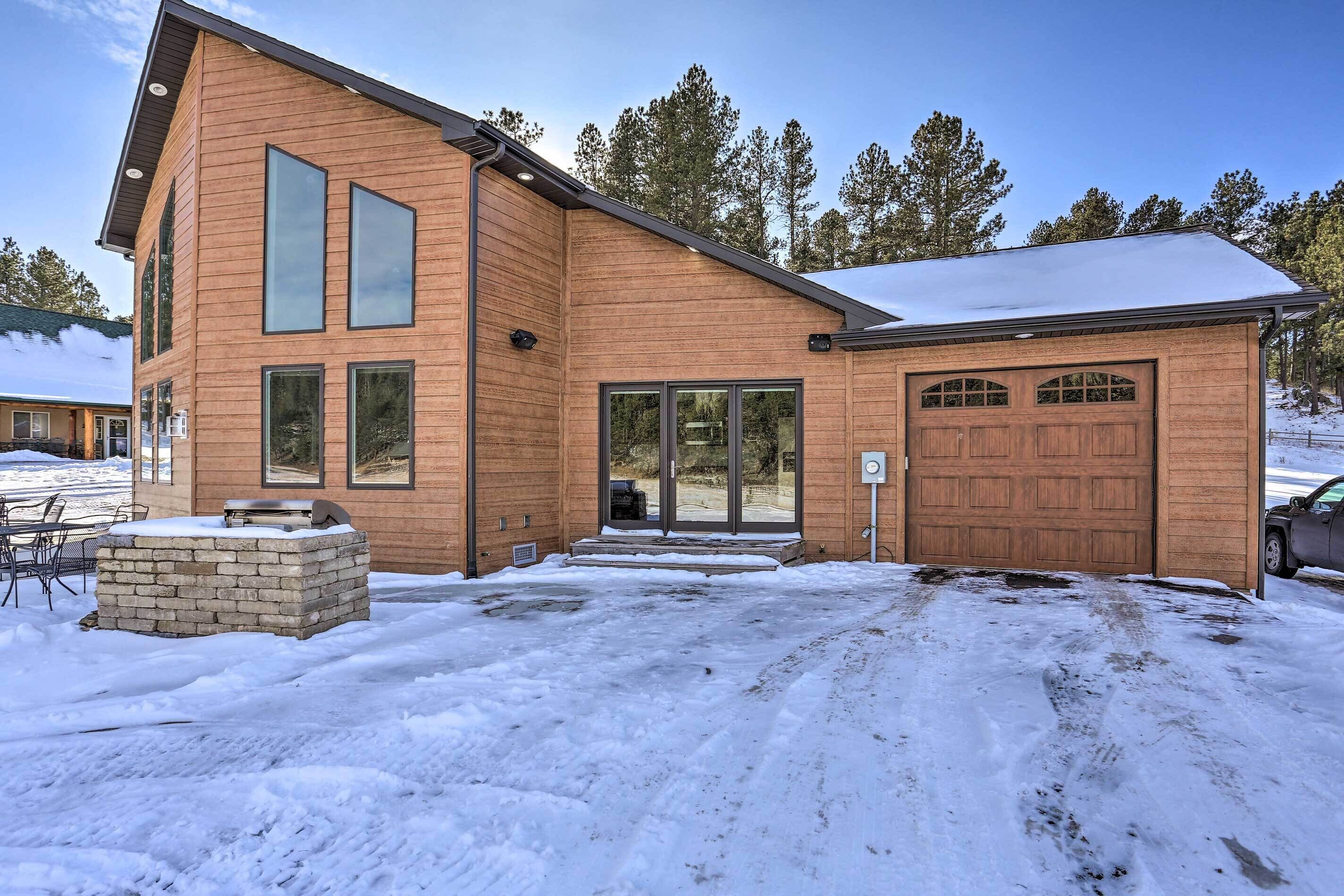 A two-story wooden house with a garage, a brick fireplace, and a snow-covered driveway.