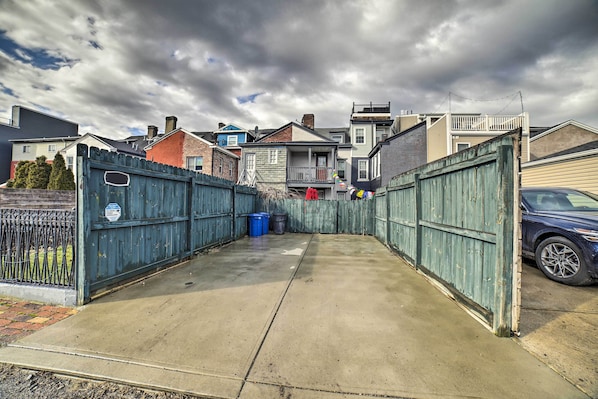 A residential area with a concrete driveway leading to a gated entrance, surrounded by houses and a parked car. - Pittsburgh Vacation Rental in Lawrenceville! (Pittsburgh)