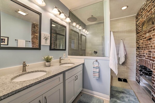 A bathroom with two sinks, a large mirror, and a shower.