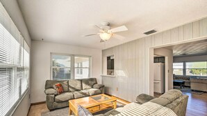 A spacious living room with a ceiling fan, a sofa, a coffee table, and a kitchen area visible through an open doorway. - Punta Gorda Home With Backyard ~ 1 Mile to Dtwn! (Punta Gorda)