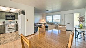 A modern kitchen with a microwave, stove, and refrigerator. There is a dining area with a wooden table and chairs. The room has hardwood flooring and large windows. - Punta Gorda Home With Backyard ~ 1 Mile to Dtwn! (Punta Gorda)
